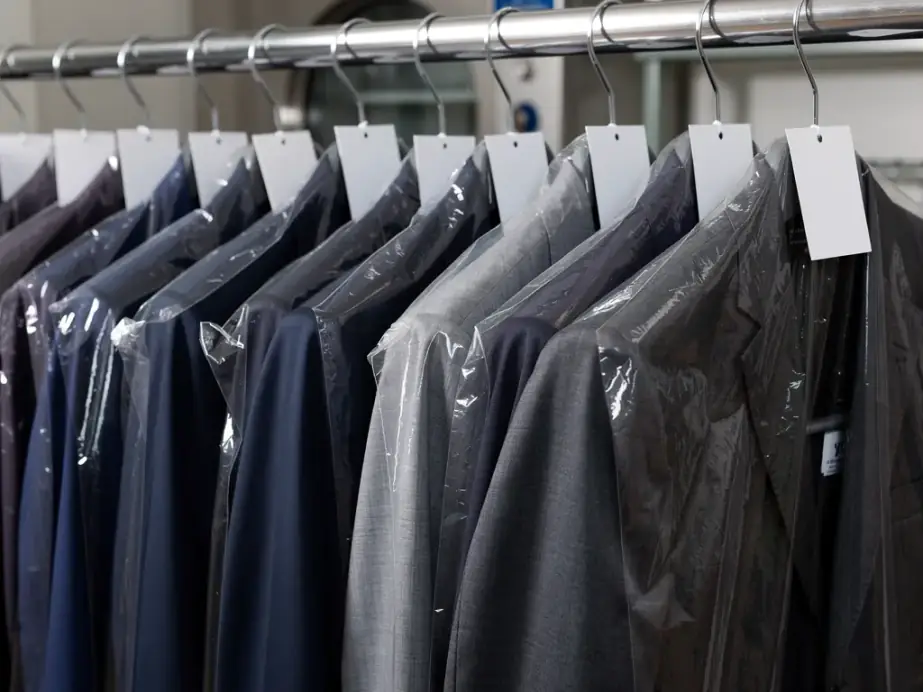 Pressed suit jackets in clear film on wire hangers, a blank tag pinned at each shoulder
